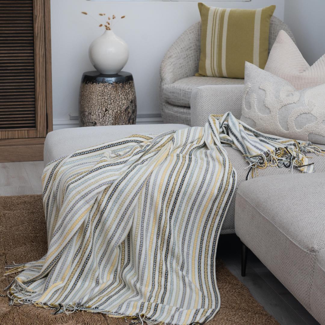 A Lyric Candy Stripe throw, featuring vibrant stripes in a playful and colorful pattern, draped over a sofa. Perfect for adding charm and personality to any lodge or guesthouse room. #LodgeLuxury #GuestExperience #PremiumBlankets #HospitalityExcellence #ProudlySouthAfrican