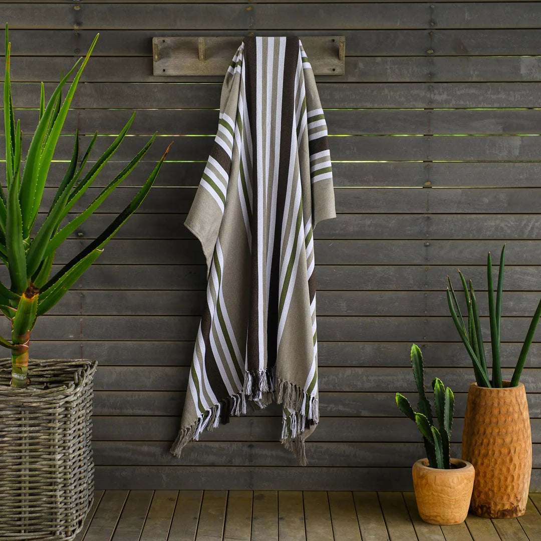 A Protea Pinstripe throw  hanging neatly on a wooden coat rack. Its hand-knotted fringes and versatile design make it perfect for both indoor and outdoor use. #GuestSatisfaction #UpgradeYourLodge #LodgeLife