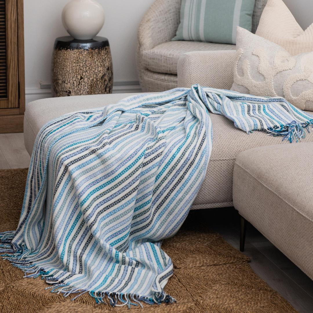 A Lyric Candy Stripe throw, featuring vibrant stripes in a playful and colorful pattern, draped over a rustic wooden chair. Perfect for adding charm and personality to any lodge or guesthouse room. #LodgeLuxury #GuestExperience #PremiumBlankets #HospitalityExcellence #ProudlySouthAfrican